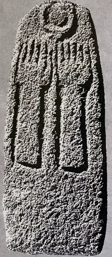 Hoher, oben abgerundeter Stein mit rauer Oberfläche; im oberen Teil eine Mondsichel, darunter zwei lange, nach oben gestreckte Arme mit gespreizten Fingern als Relief.