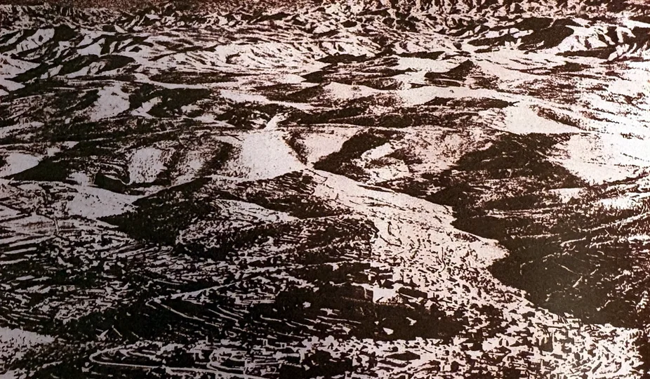 Kontrastreiches Schwarzweißfoto einer kahlen, stark zerfurchten Hügellandschaft mit Terrassen im Vordergrund, die sich bis zum Horizont fortsetzt.