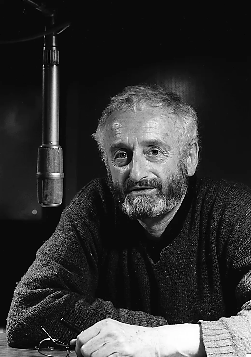 Manfred Voegele im Studio, am Tisch vor einem Mikrofon sitzend, Schwarzweißfoto